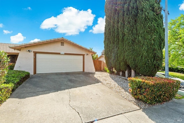 view of front facade featuring stucco siding, fence, concrete driveway, and a garage