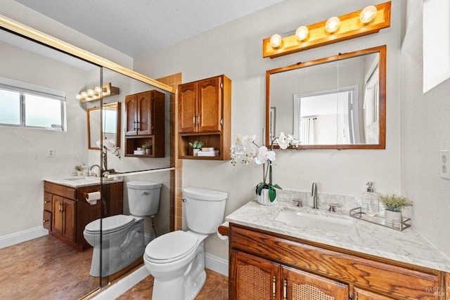 bathroom with toilet, vanity, a textured ceiling, and baseboards