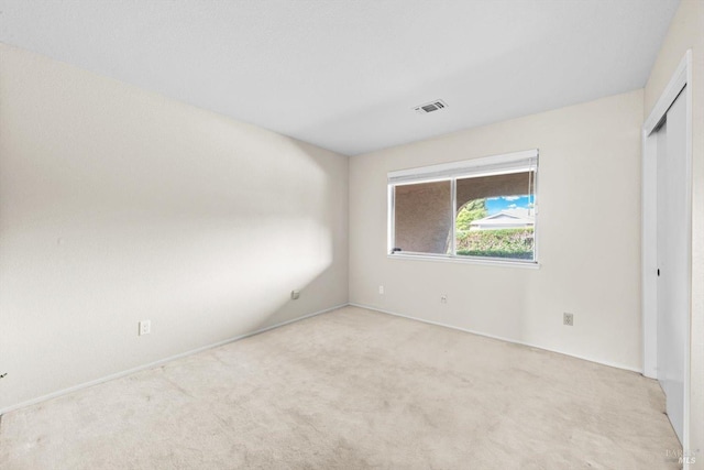 unfurnished bedroom with carpet flooring, visible vents, and a closet