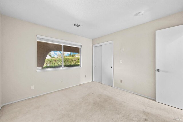 unfurnished bedroom featuring baseboards, carpet floors, visible vents, and a closet