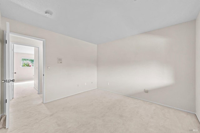 unfurnished room featuring light carpet and baseboards