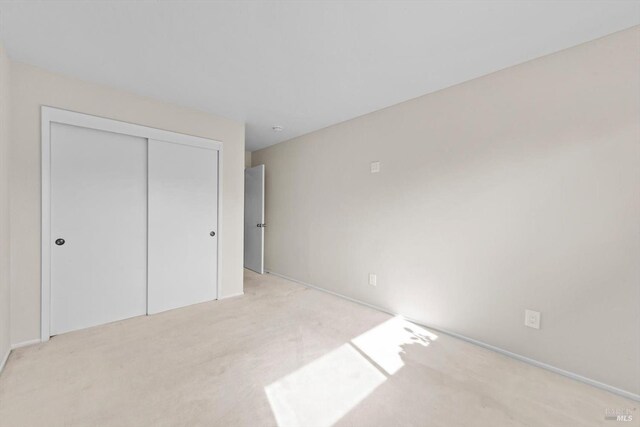 unfurnished bedroom featuring baseboards, carpet floors, and a closet