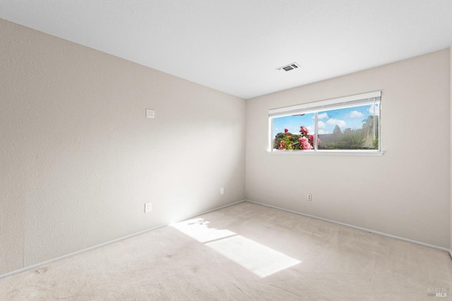 carpeted empty room featuring baseboards and visible vents