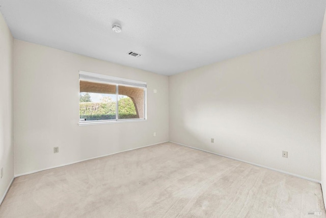 spare room featuring carpet, visible vents, and baseboards