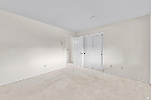 unfurnished bedroom featuring baseboards, carpet flooring, and a closet