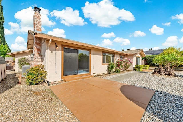 back of property featuring stucco siding, a patio area, a chimney, and central AC