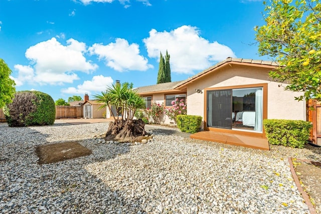 back of property featuring stucco siding, fence, an outbuilding, and a storage unit