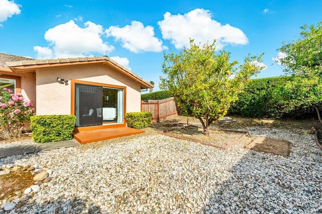 back of house featuring a tiled roof, stucco siding, and fence