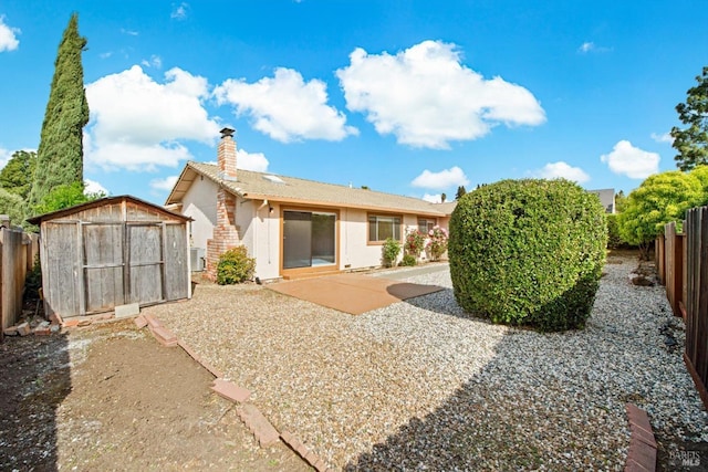 rear view of house featuring a fenced backyard, a chimney, a patio area, a shed, and stucco siding