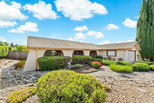 ranch-style house with stucco siding, an attached garage, fence, and a tiled roof