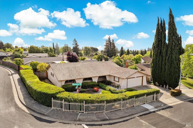 view of front of home featuring a fenced front yard, a residential view, stucco siding, an attached garage, and a tile roof