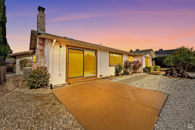 back of house featuring a patio area, a chimney, cooling unit, and stucco siding