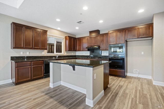 kitchen featuring light wood-type flooring, visible vents, under cabinet range hood, and black appliances
