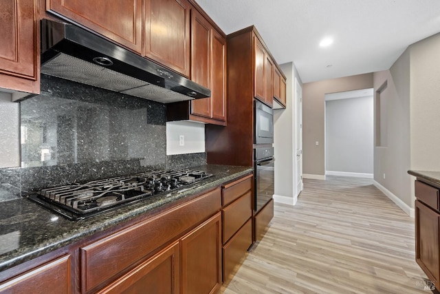 kitchen featuring baseboards, under cabinet range hood, light wood-style floors, and black appliances