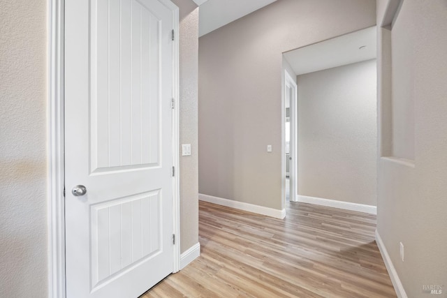 corridor featuring light wood-style flooring and baseboards