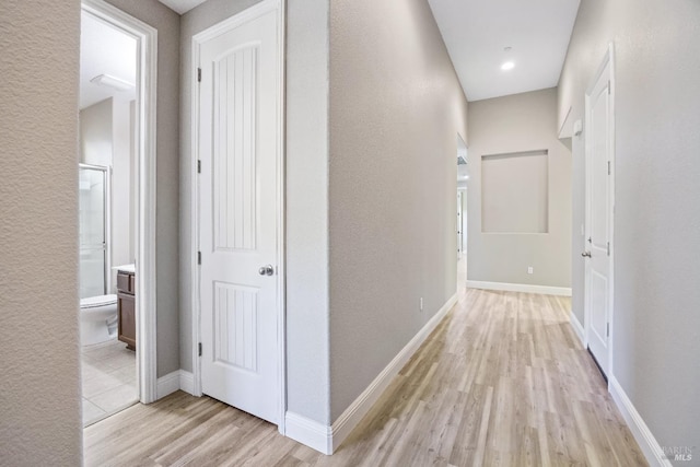corridor featuring light wood-style flooring and baseboards