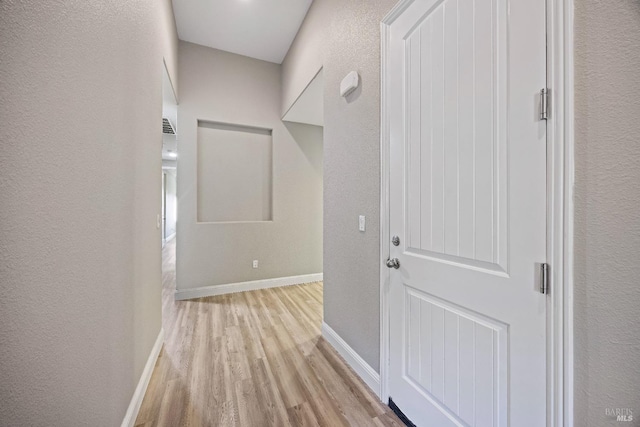 corridor with baseboards, wood finished floors, and a textured wall