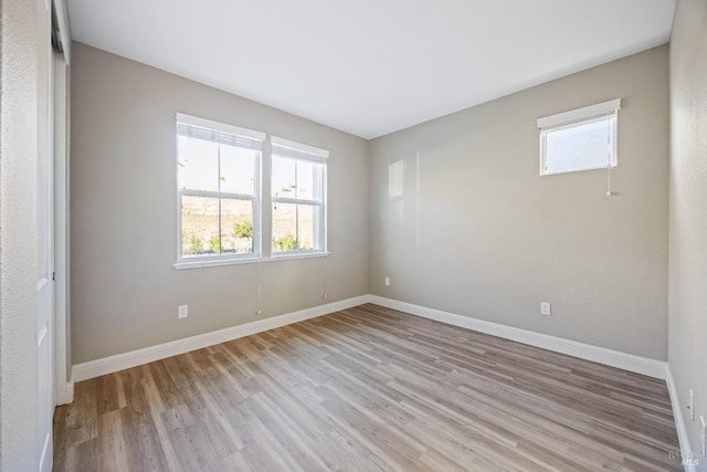 empty room with a healthy amount of sunlight, light wood finished floors, and baseboards