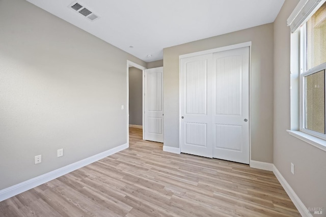 unfurnished bedroom featuring light wood-type flooring, visible vents, baseboards, and multiple windows
