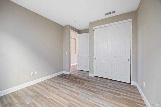 unfurnished bedroom featuring light wood finished floors, baseboards, a closet, and visible vents