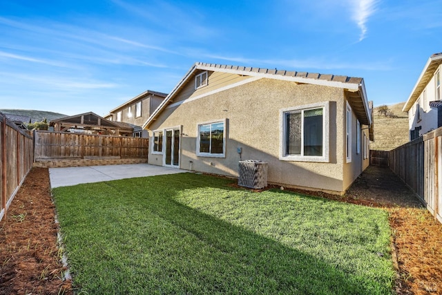 rear view of property featuring a fenced backyard, central AC, stucco siding, a patio, and a lawn