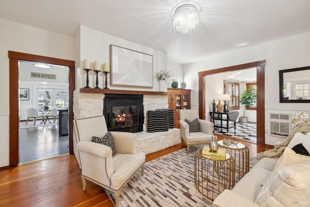 living room with a fireplace, wood finished floors, and an inviting chandelier