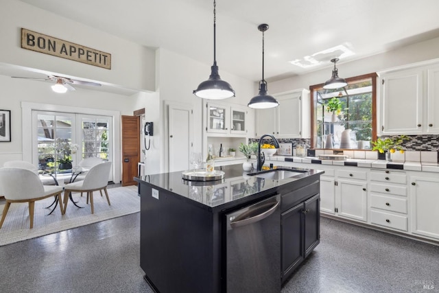 kitchen with backsplash, dishwasher, a sink, a kitchen island with sink, and white cabinetry