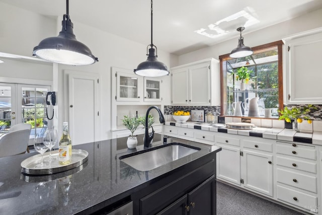 kitchen featuring decorative backsplash, white cabinetry, a sink, and hanging light fixtures