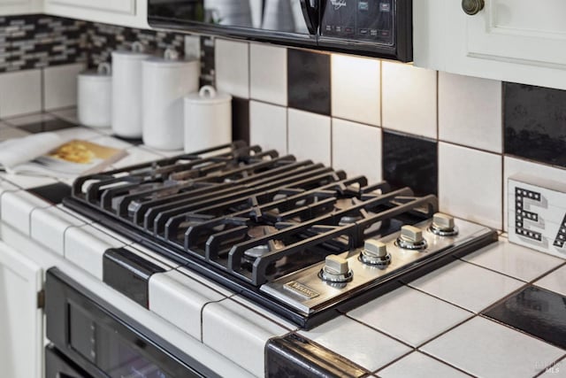 interior details with stainless steel gas stovetop, light countertops, and backsplash
