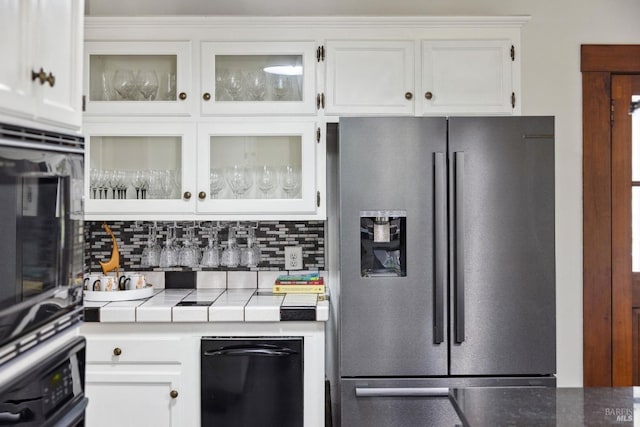 kitchen with tile countertops, white cabinets, appliances with stainless steel finishes, and tasteful backsplash