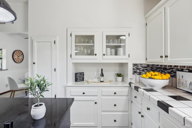 kitchen featuring white cabinets, backsplash, and glass insert cabinets