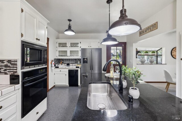 kitchen with black appliances, tasteful backsplash, a sink, and white cabinets
