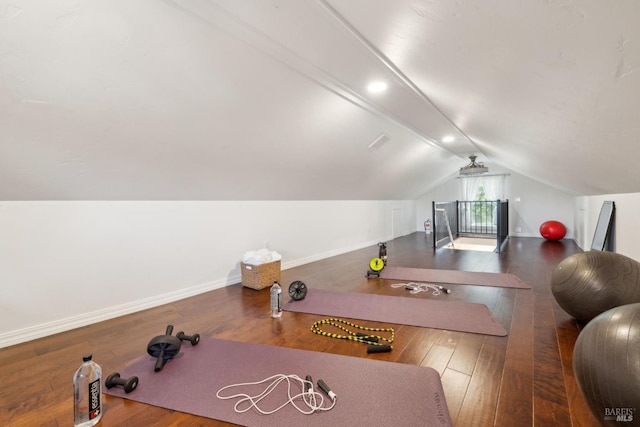 workout area featuring baseboards, lofted ceiling, and hardwood / wood-style flooring