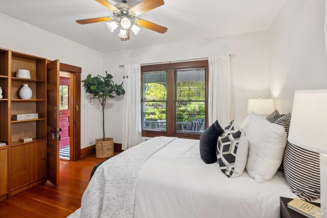 bedroom with a ceiling fan, baseboards, and dark wood-style flooring