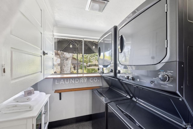 washroom with a textured ceiling, stacked washer and dryer, baseboards, and laundry area