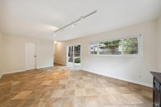 spare room featuring baseboards and rail lighting