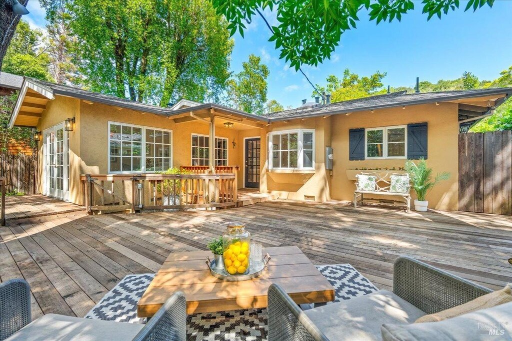 rear view of property featuring french doors, stucco siding, and a deck