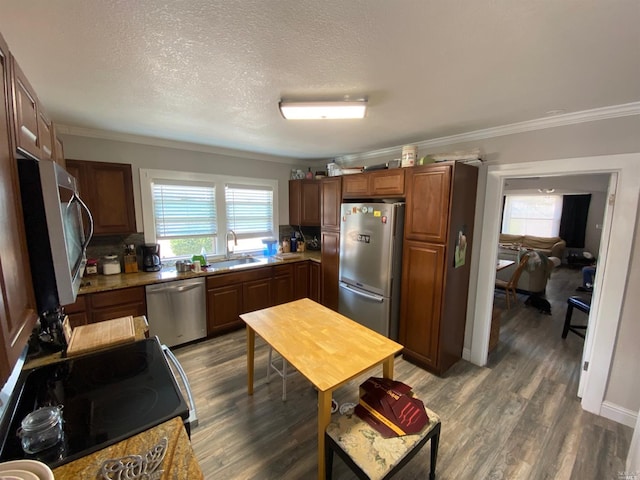 kitchen with a wealth of natural light, appliances with stainless steel finishes, ornamental molding, and a sink