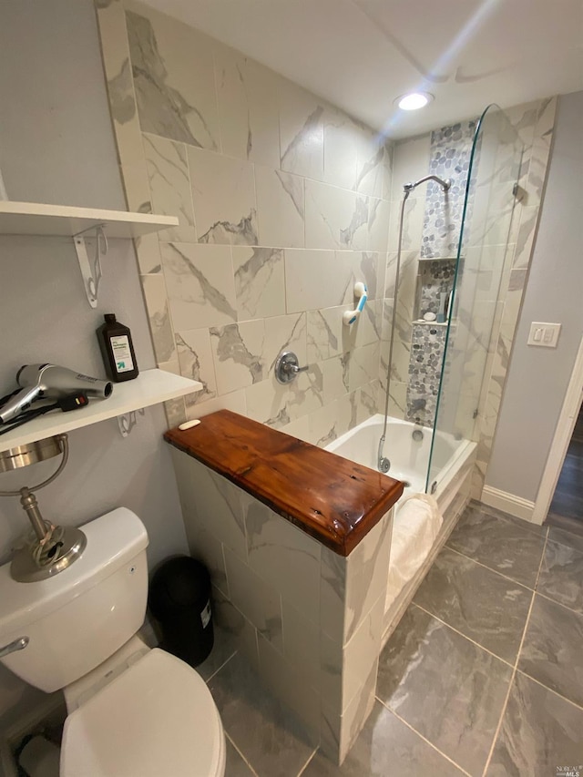 bathroom with tiled shower / bath combo, toilet, marble finish floor, and recessed lighting