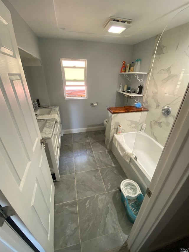 bathroom with toilet, a tub to relax in, vanity, marble finish floor, and baseboards