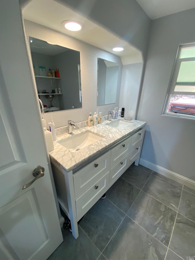 full bath with baseboards, a sink, and double vanity