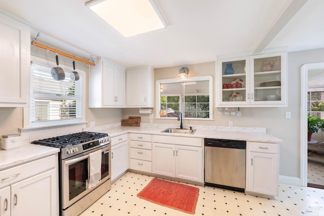 kitchen featuring light floors, a wealth of natural light, stainless steel appliances, and a sink