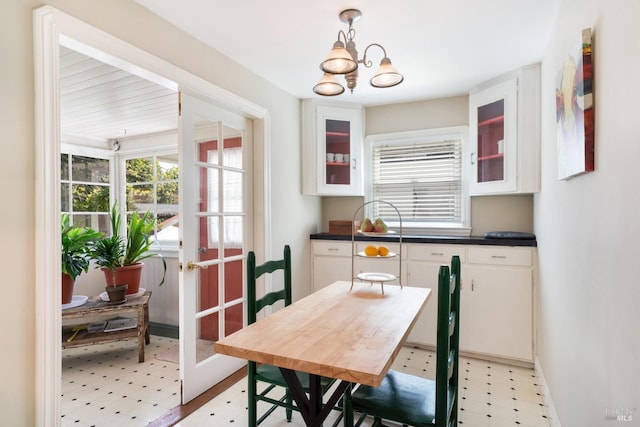 dining space with light floors, plenty of natural light, baseboards, and an inviting chandelier