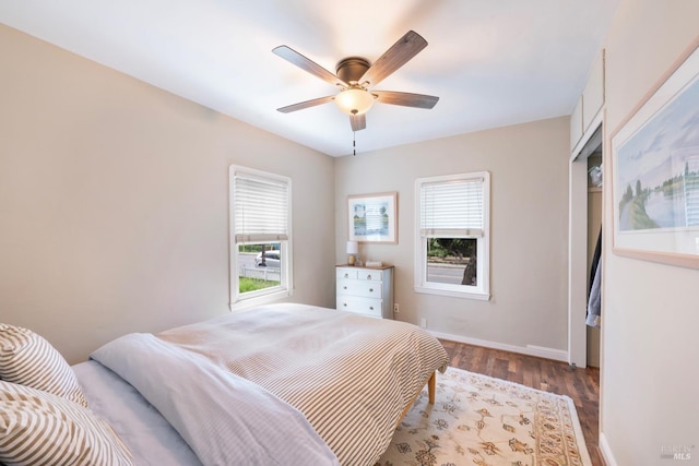 bedroom featuring wood finished floors, a ceiling fan, baseboards, and multiple windows