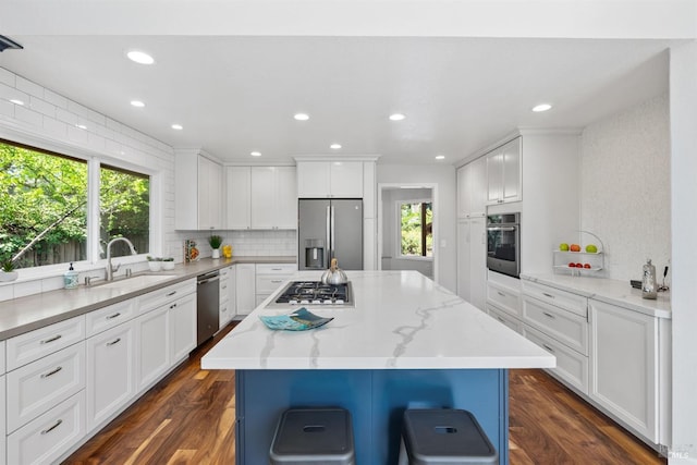 kitchen with stainless steel appliances, a sink, white cabinetry, and tasteful backsplash