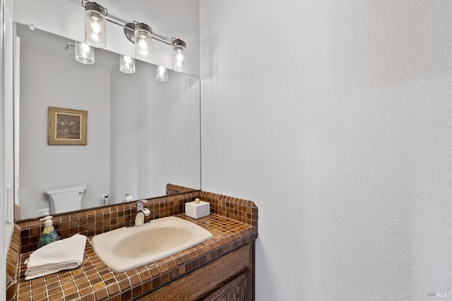 bathroom with backsplash, toilet, and vanity
