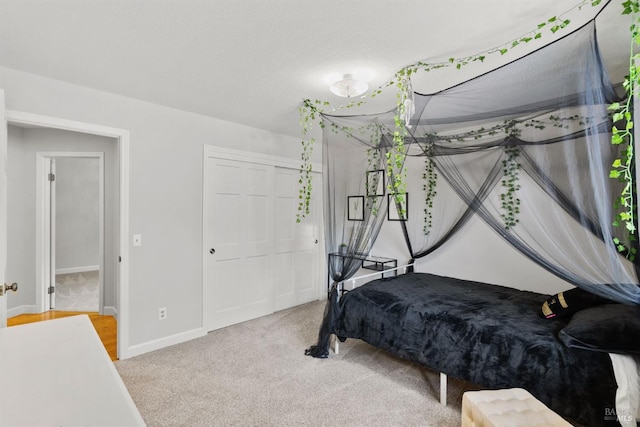 bedroom featuring baseboards, a closet, and light colored carpet