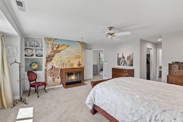 carpeted bedroom with baseboards, a glass covered fireplace, visible vents, and recessed lighting