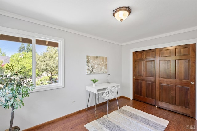 bedroom with baseboards, crown molding, wood finished floors, and a closet