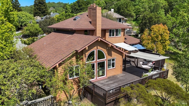 back of property featuring a wooden deck, a shingled roof, and a chimney